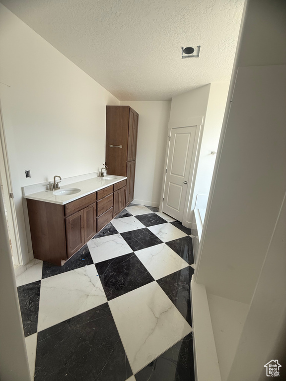 Full bath featuring a garden tub, a textured ceiling, and double vanity