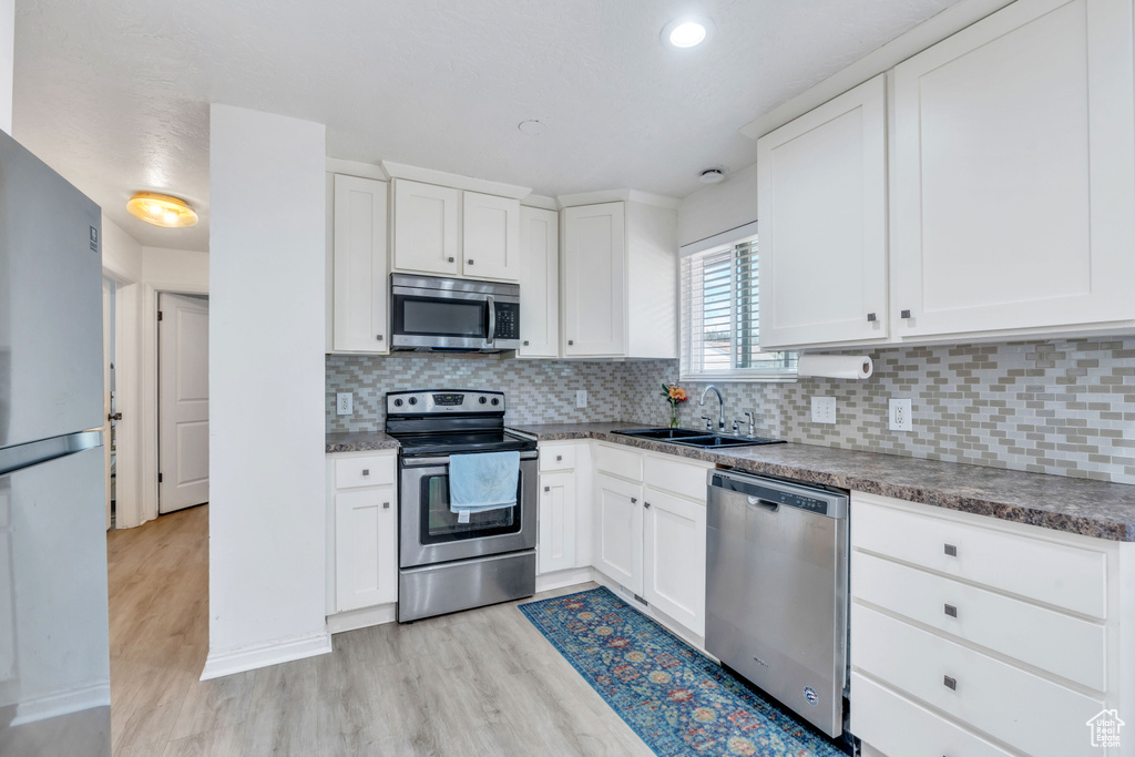 Kitchen featuring light wood-type flooring, sink, appliances with stainless steel finishes, and white cabinets