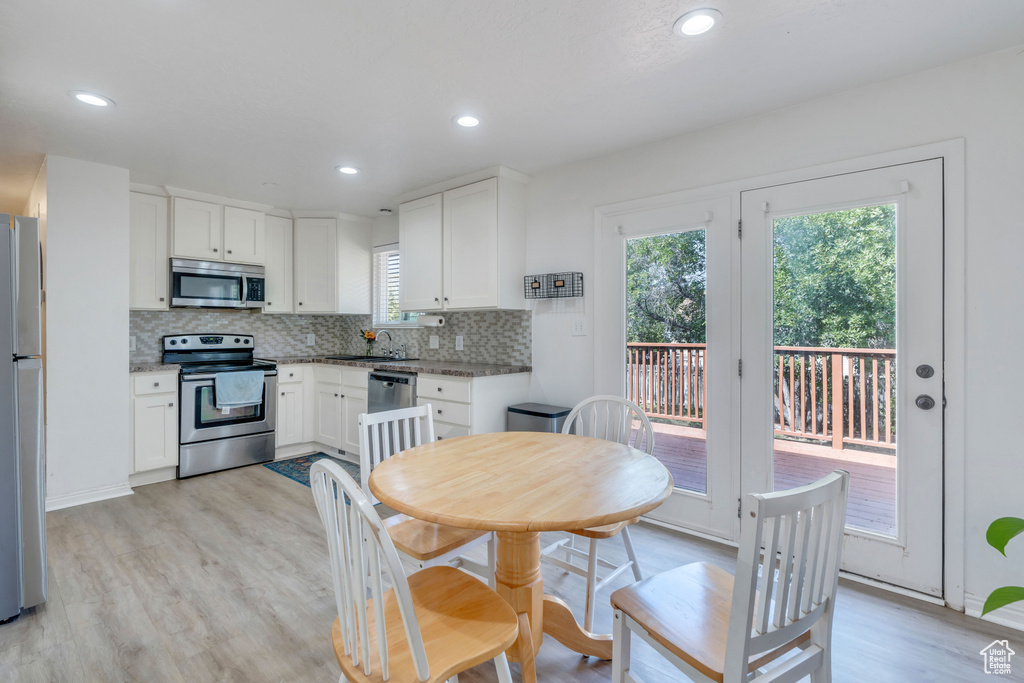 Kitchen featuring light hardwood / wood-style flooring, stainless steel appliances, backsplash, and white cabinetry