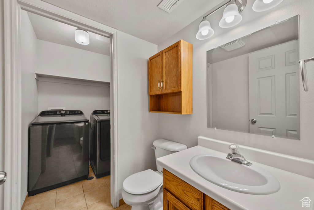 Bathroom with tile patterned floors, toilet, washing machine and clothes dryer, and vanity