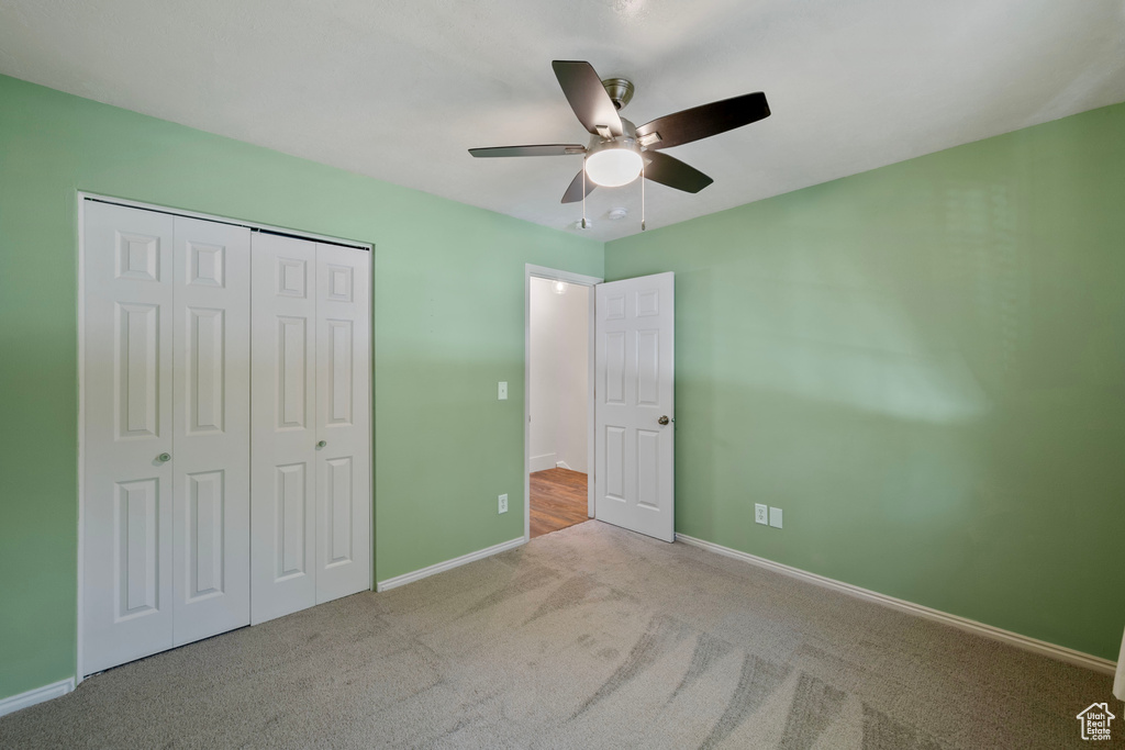 Unfurnished bedroom featuring ceiling fan, a closet, and light carpet