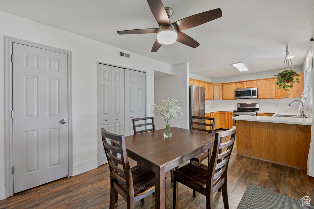 Dining room featuring dark wood-type flooring, ceiling fan, and sink