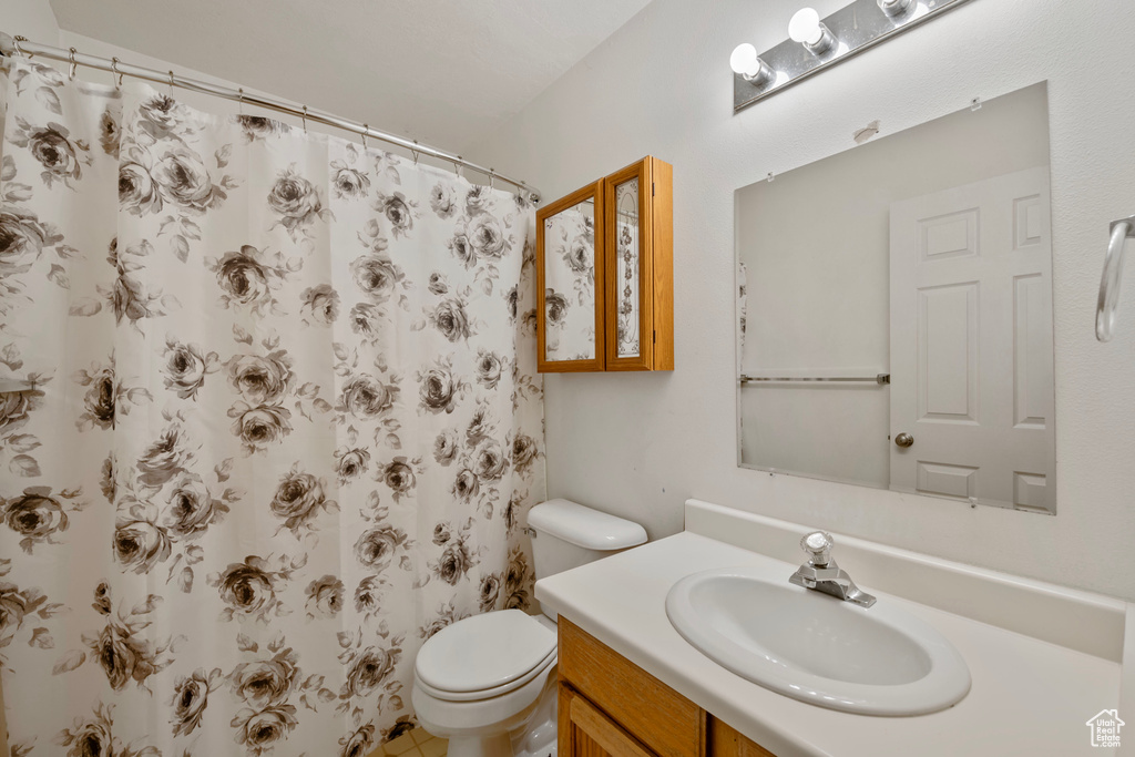 Bathroom featuring a shower with curtain, toilet, and vanity