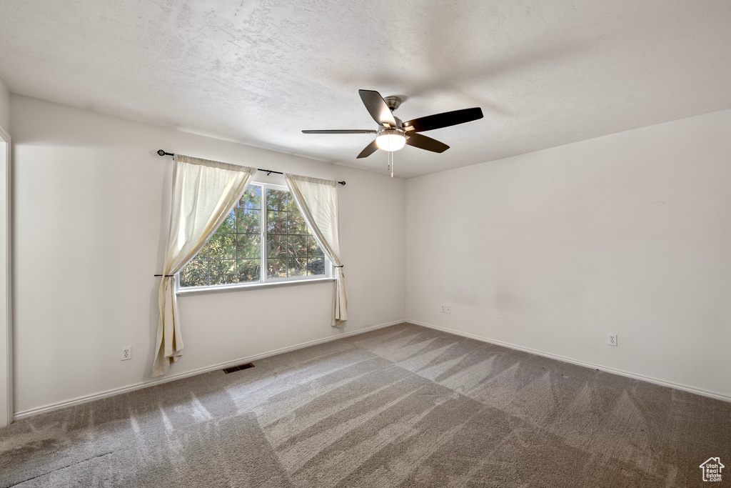 Carpeted spare room with ceiling fan and a textured ceiling