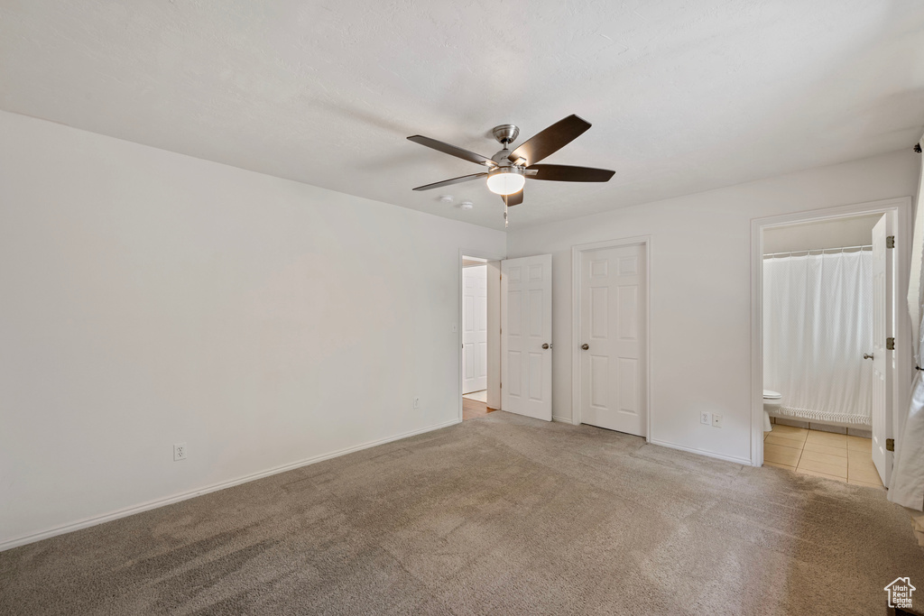 Unfurnished bedroom with ceiling fan, light colored carpet, and ensuite bathroom