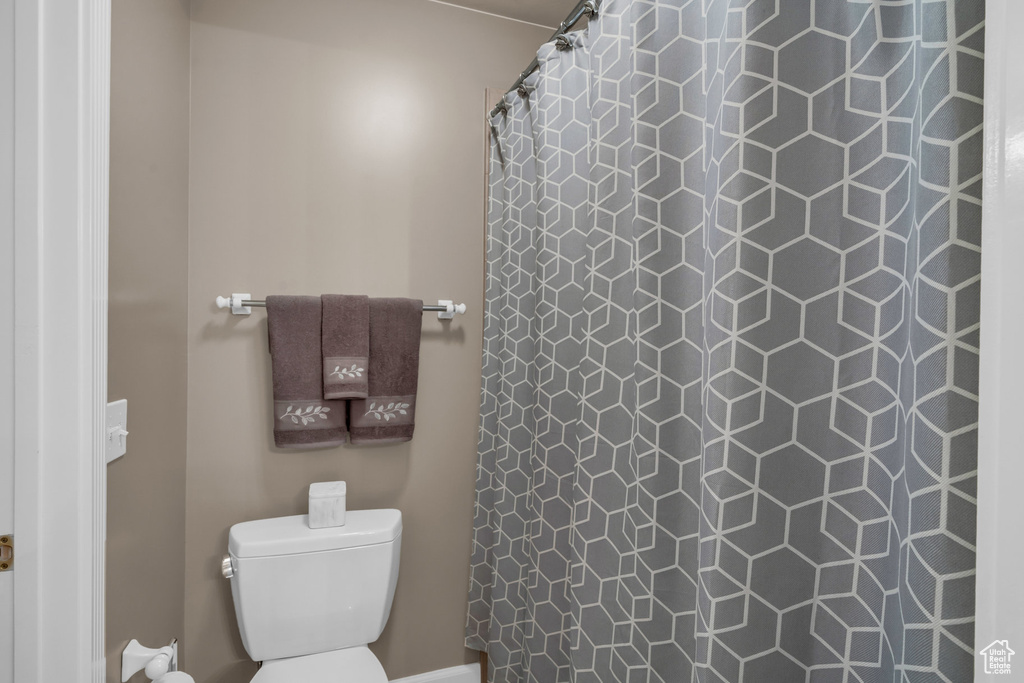 Bathroom featuring a shower with shower curtain and toilet