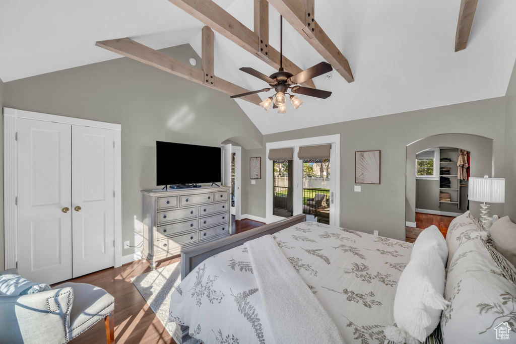 Bedroom with access to exterior, arched walkways, dark wood finished floors, a closet, and beamed ceiling