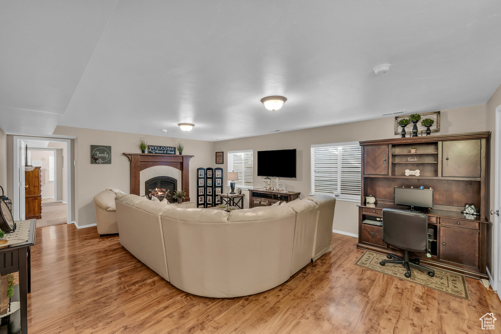 Living room with a lit fireplace, light wood-style flooring, and baseboards