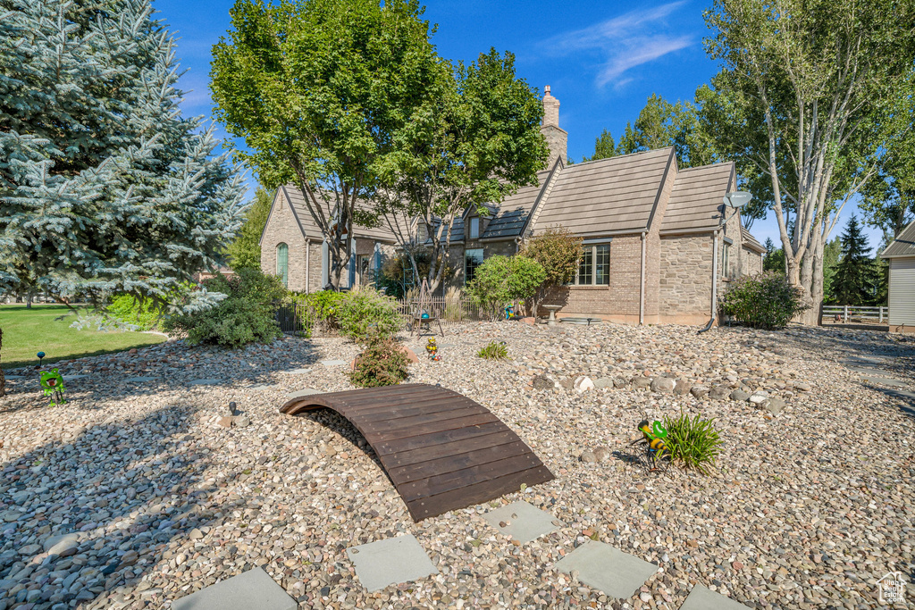 Rear view of house featuring a chimney and brick siding