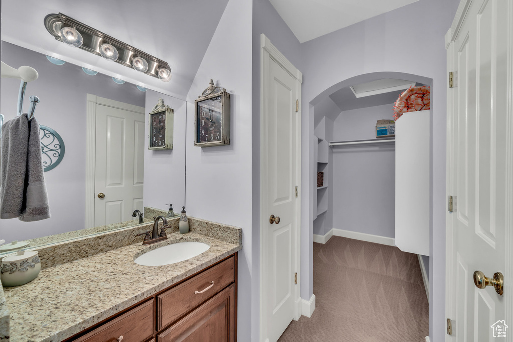 Bathroom with a spacious closet, vanity, and baseboards