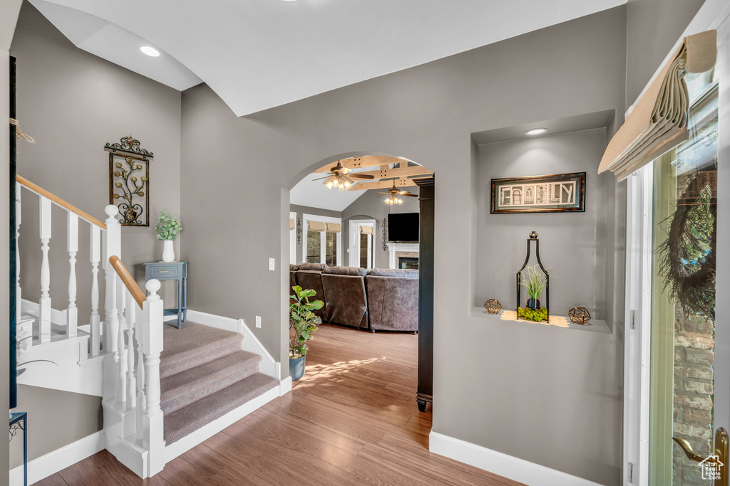 Foyer featuring arched walkways, stairway, baseboards, and wood finished floors