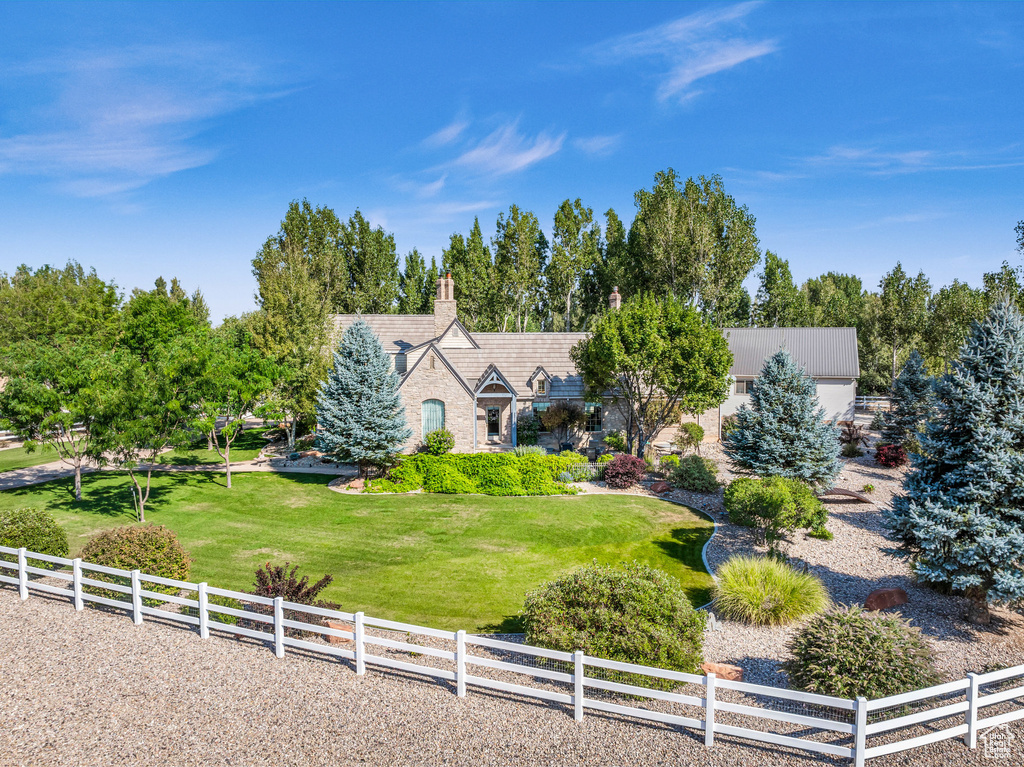 View of front of home featuring a front yard, a rural view, fence, and a chimney