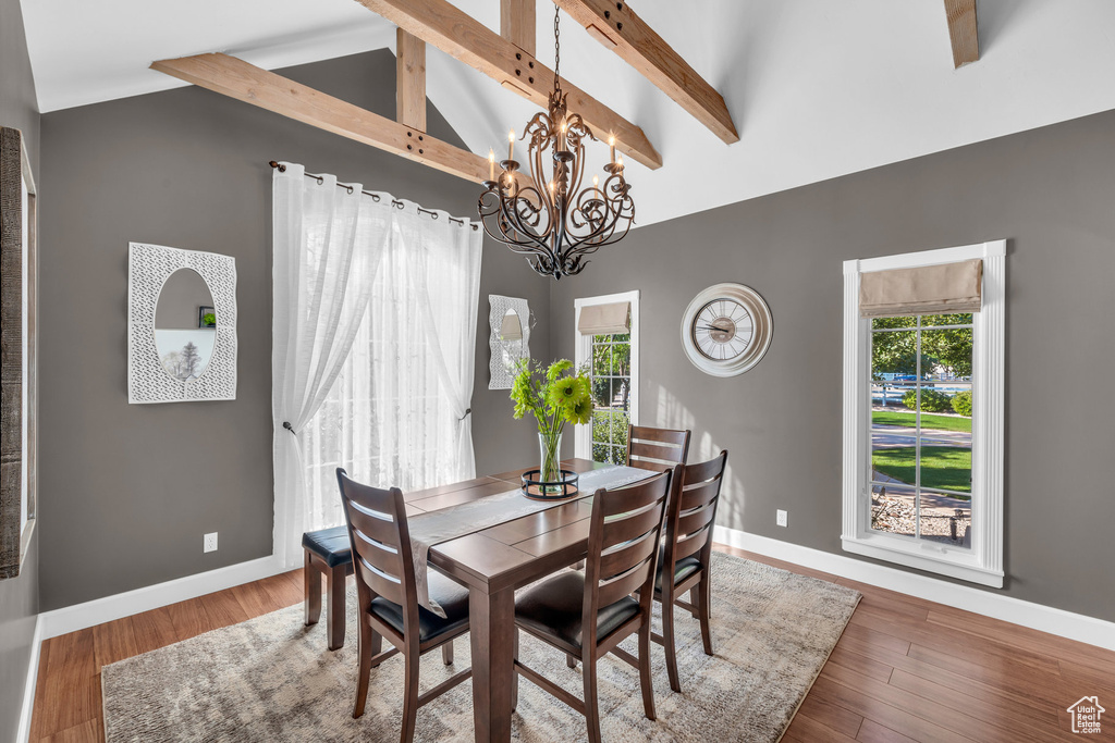 Dining room featuring hardwood / wood-style floors, a chandelier, and lofted ceiling with beams