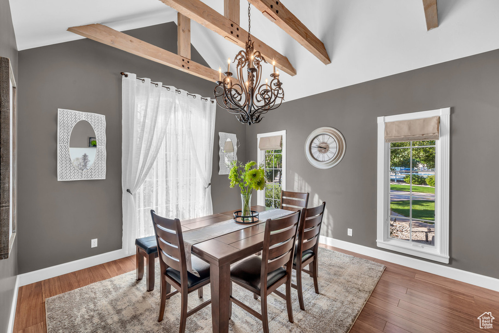 Dining room featuring a notable chandelier, beam ceiling, baseboards, and wood finished floors