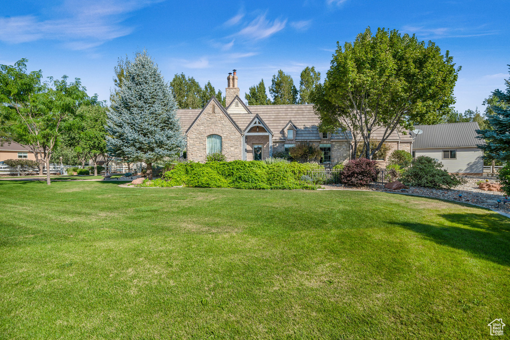 Tudor house with stone siding, a chimney, and a front lawn
