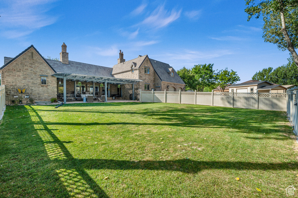 Rear view of house featuring a fenced backyard, brick siding, a yard, a pergola, and a patio area