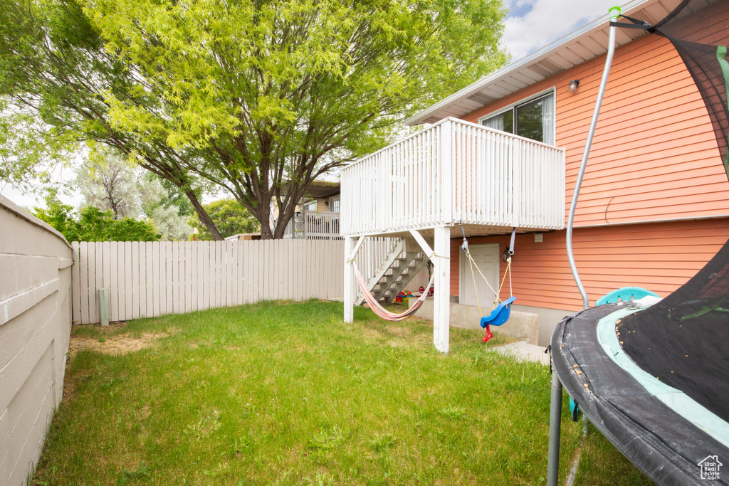 View of yard featuring a wooden deck and a trampoline