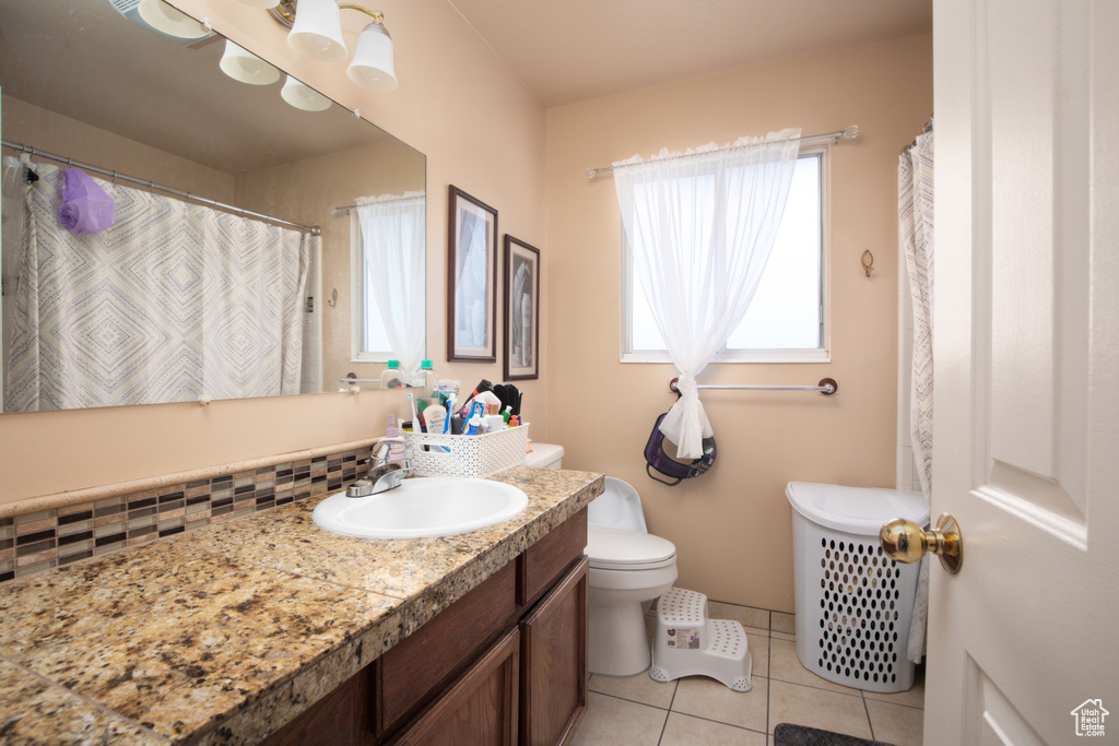 Bathroom featuring toilet, tile patterned floors, vanity, decorative backsplash, and a shower with curtain