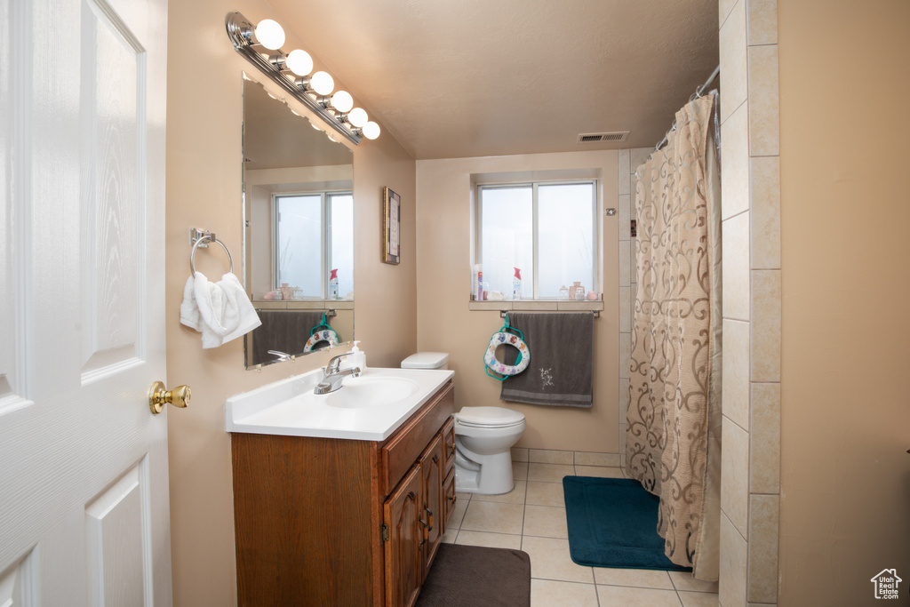 Bathroom featuring vanity, toilet, curtained shower, and tile patterned flooring