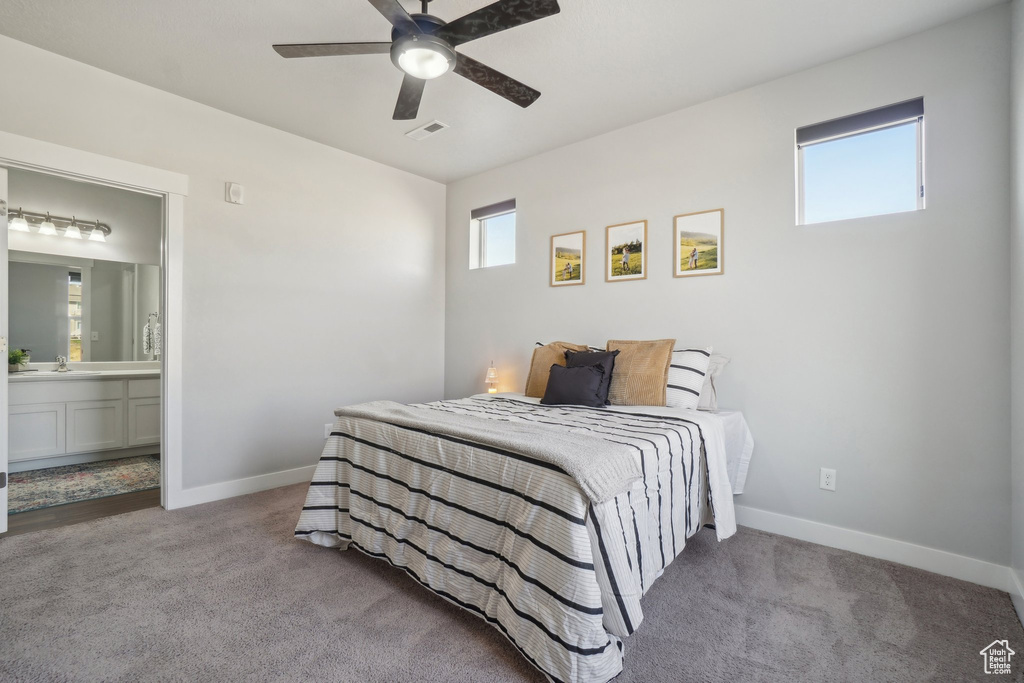 Bedroom featuring ensuite bath, sink, ceiling fan, and carpet floors