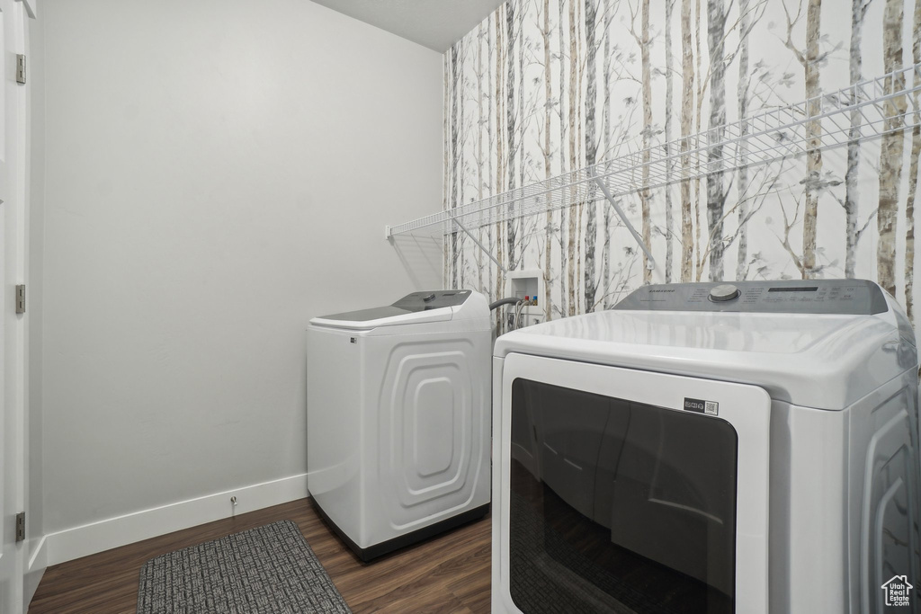 Washroom with dark hardwood / wood-style flooring and washing machine and clothes dryer