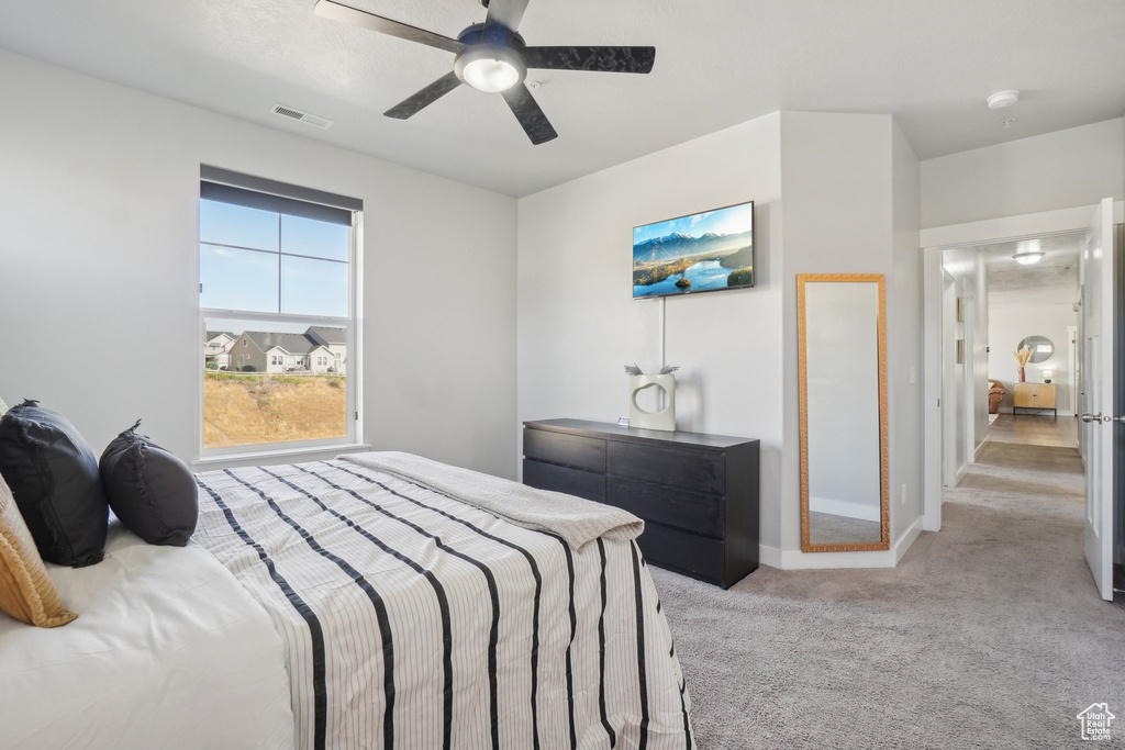 Bedroom with ceiling fan and light carpet