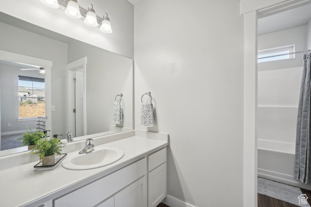 Bathroom with hardwood / wood-style floors, ceiling fan, a shower with shower curtain, and vanity