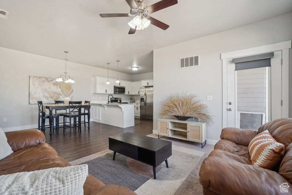 Living room with hardwood / wood-style floors, ceiling fan with notable chandelier, and sink