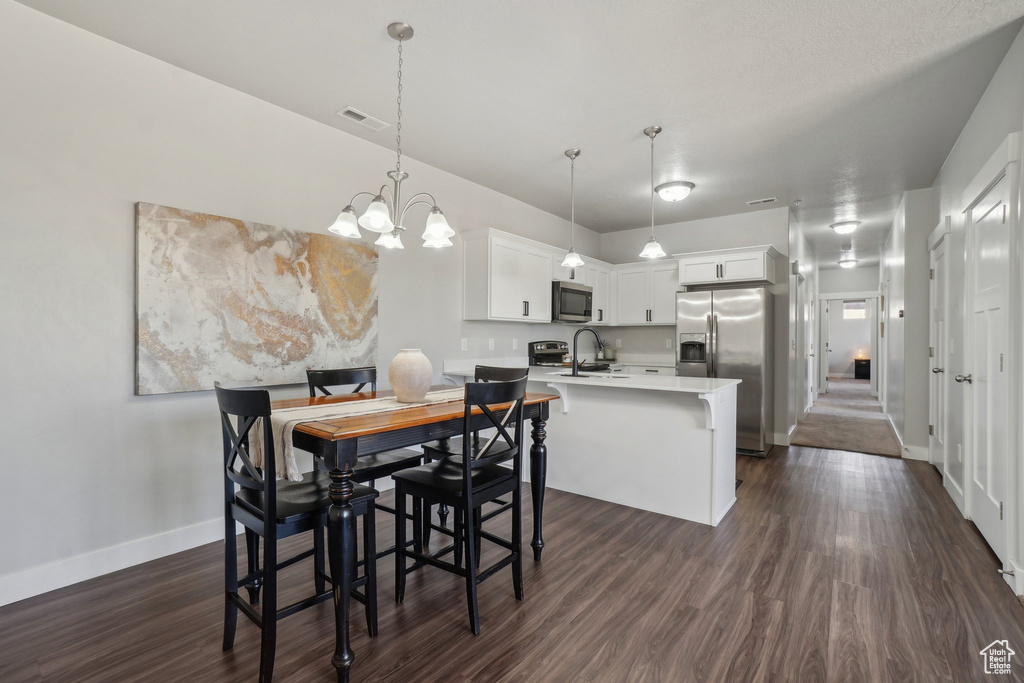 Dining area featuring an inviting chandelier, sink, and dark hardwood / wood-style flooring