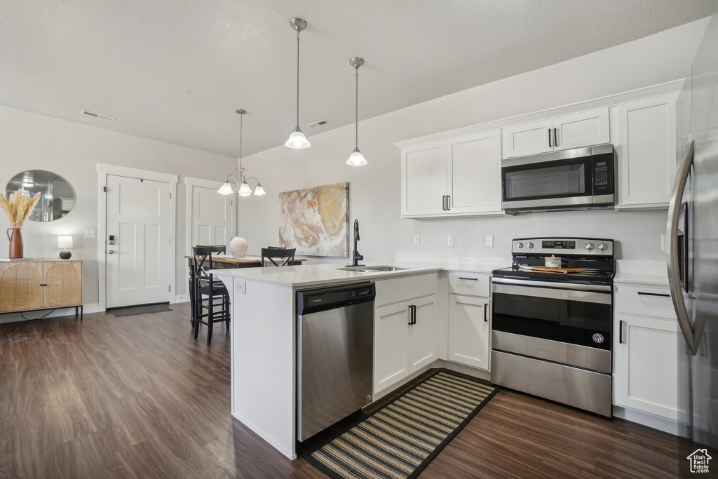 Kitchen with kitchen peninsula, appliances with stainless steel finishes, and white cabinetry