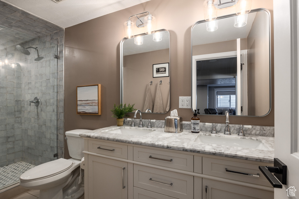 Bathroom featuring tiled shower, vanity, and toilet