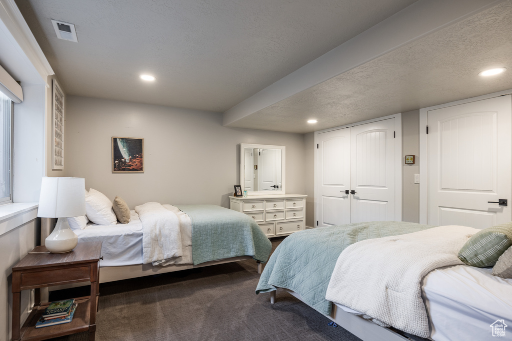 Carpeted bedroom featuring a textured ceiling and a closet