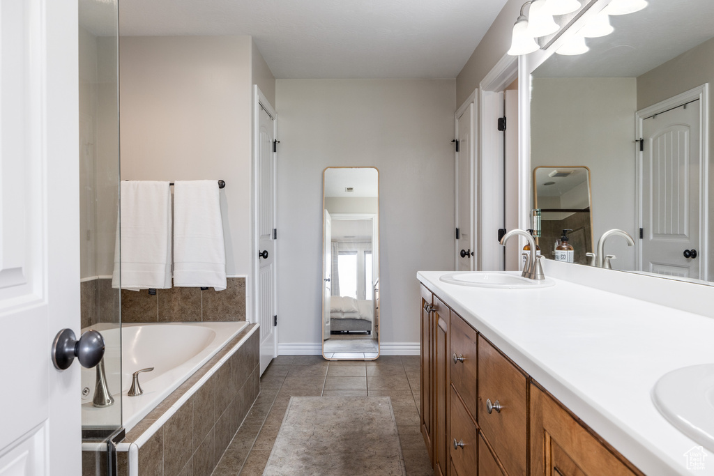 Bathroom featuring vanity, tile patterned floors, and tiled bath