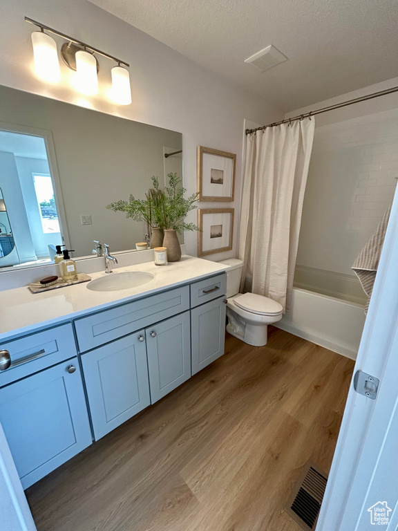 Full bathroom with vanity, hardwood / wood-style floors, toilet, and shower / tub combo