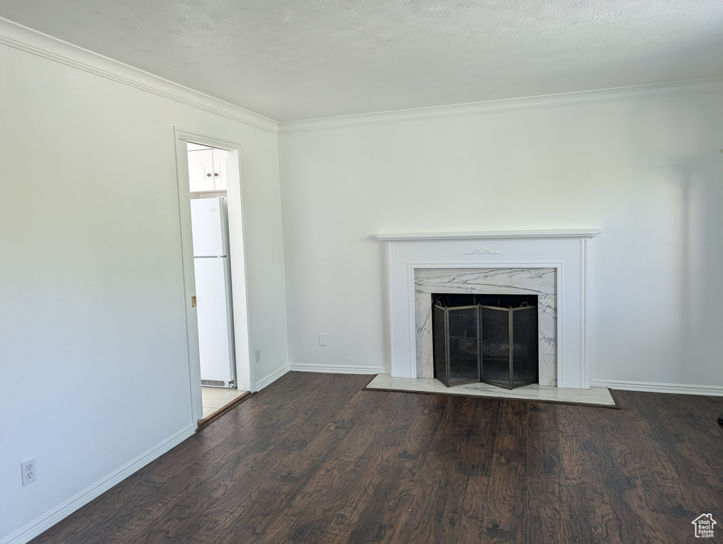 Unfurnished living room with a textured ceiling, ornamental molding, dark hardwood / wood-style flooring, and a fireplace