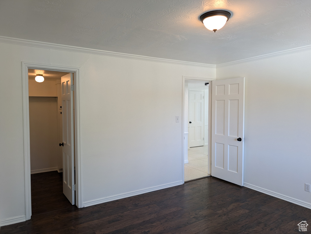 Unfurnished room featuring ornamental molding, dark wood-type flooring, and a textured ceiling