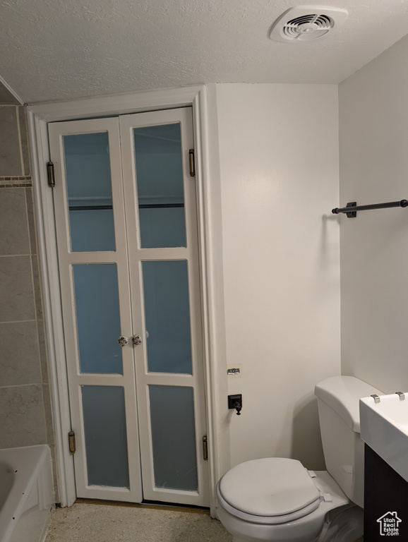 Bathroom with vanity, toilet, and a textured ceiling