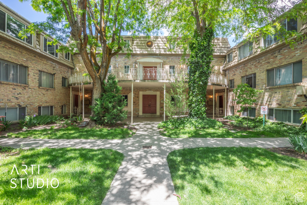 View of front of house featuring a balcony and a front yard