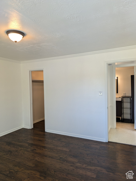 Empty room with crown molding, dark hardwood / wood-style floors, and a textured ceiling