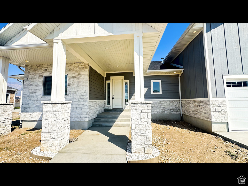 Property entrance with a garage and covered porch