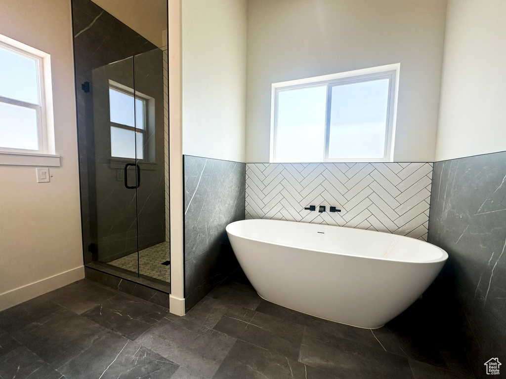 Bathroom featuring tile walls and shower with separate bathtub