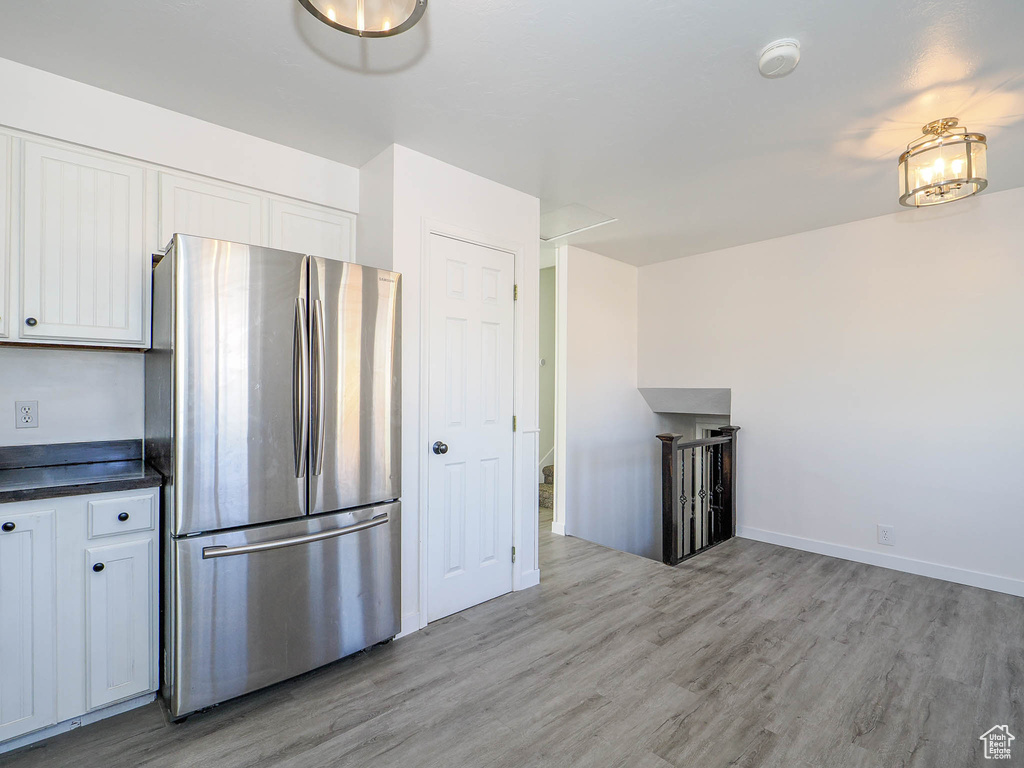 Kitchen with light wood-type flooring, white cabinets, and stainless steel fridge