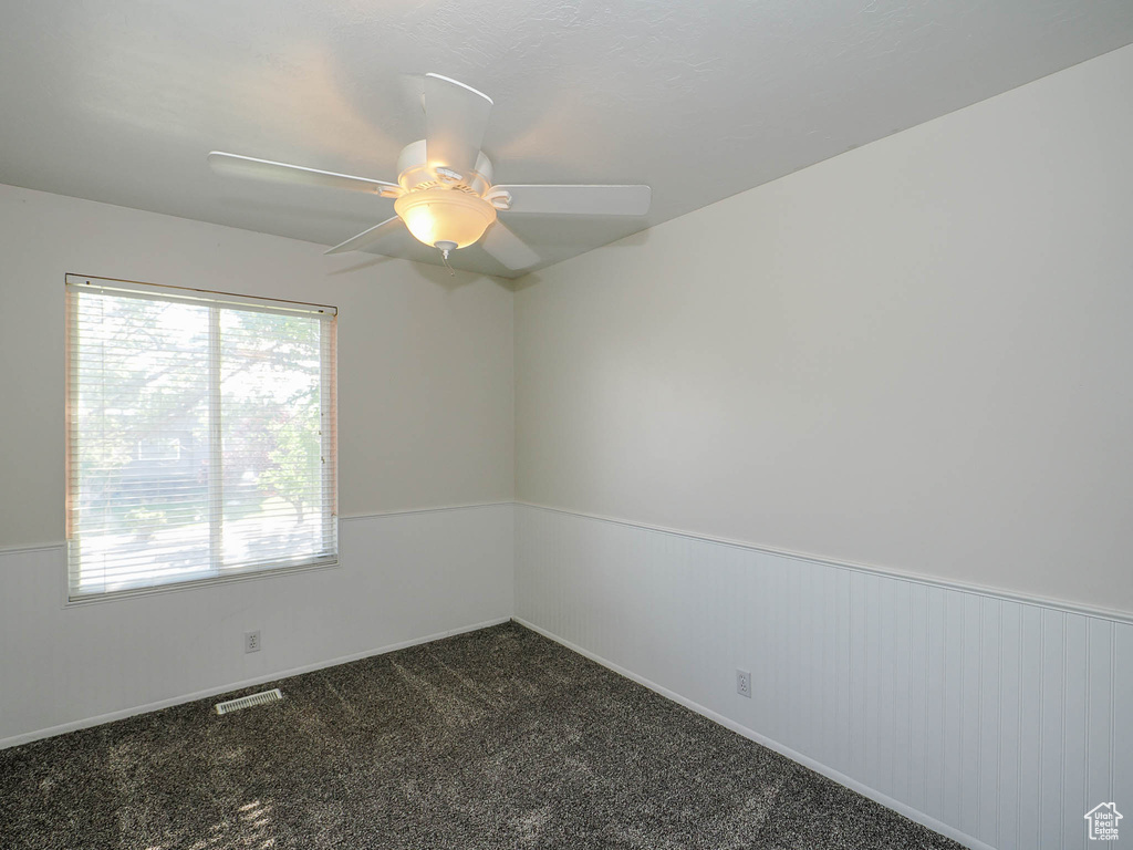 Empty room featuring ceiling fan and carpet flooring