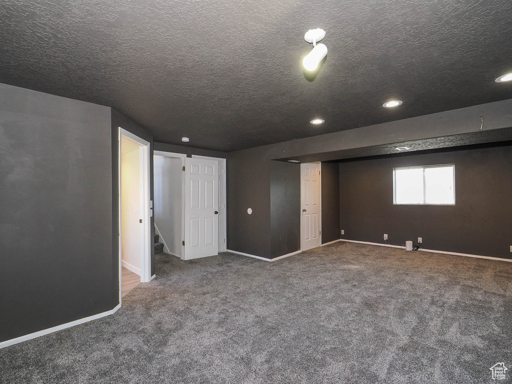 Basement featuring a textured ceiling and carpet floors