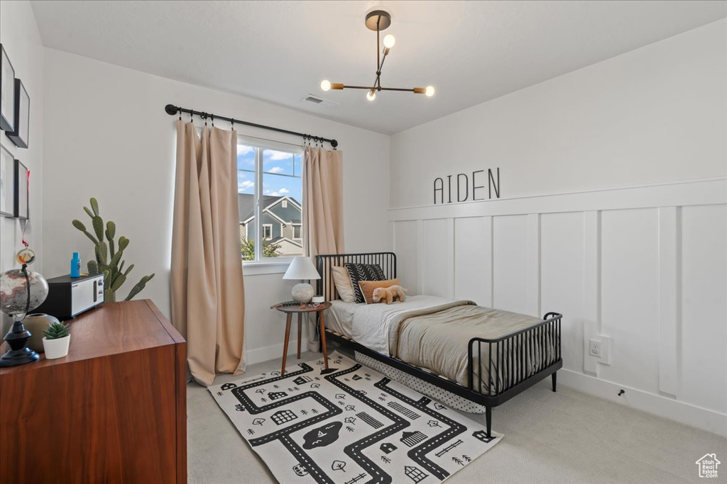 Bedroom with a chandelier and light carpet