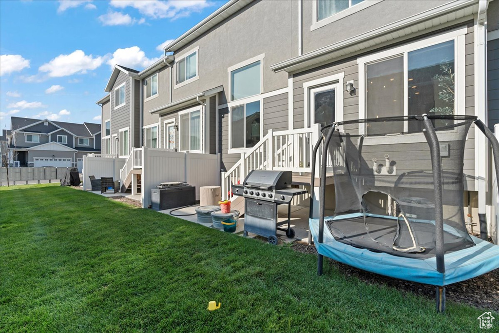 Rear view of property featuring a yard and a trampoline