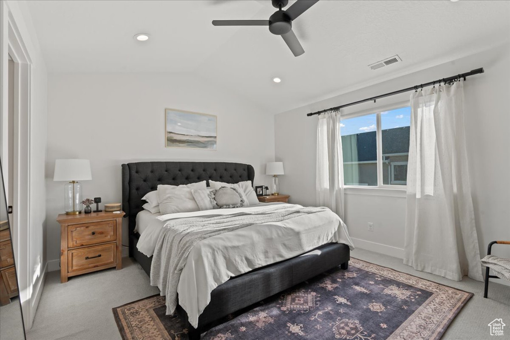 Bedroom with light colored carpet, ceiling fan, and vaulted ceiling