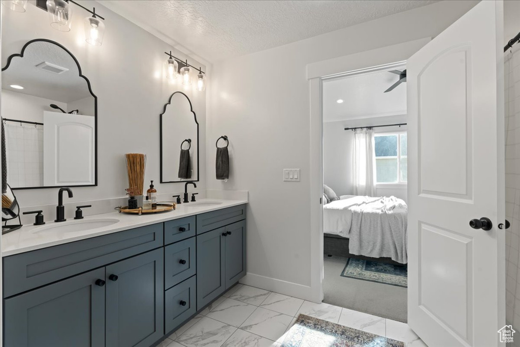 Bathroom featuring a textured ceiling, vanity, and ceiling fan