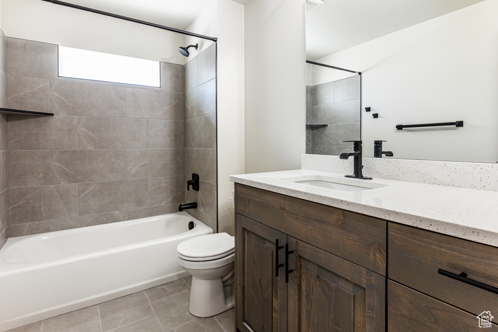 Full bathroom featuring vanity, tiled shower / bath combo, toilet, and tile patterned flooring