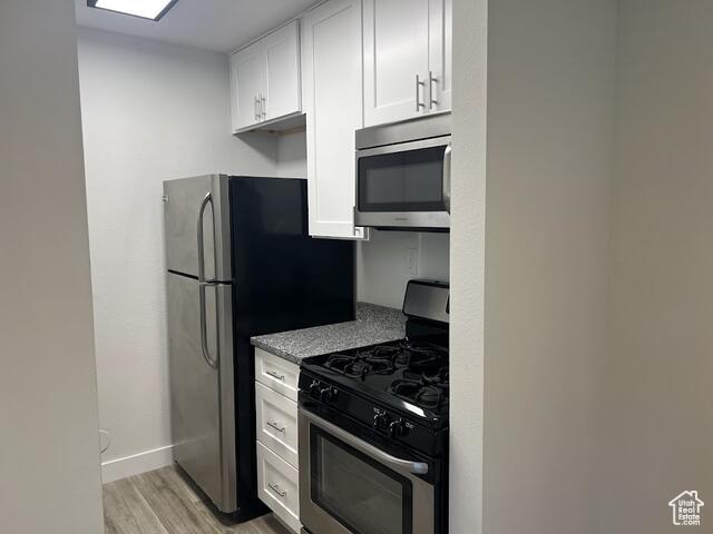 Kitchen featuring stainless steel appliances, light wood-type flooring, and white cabinetry